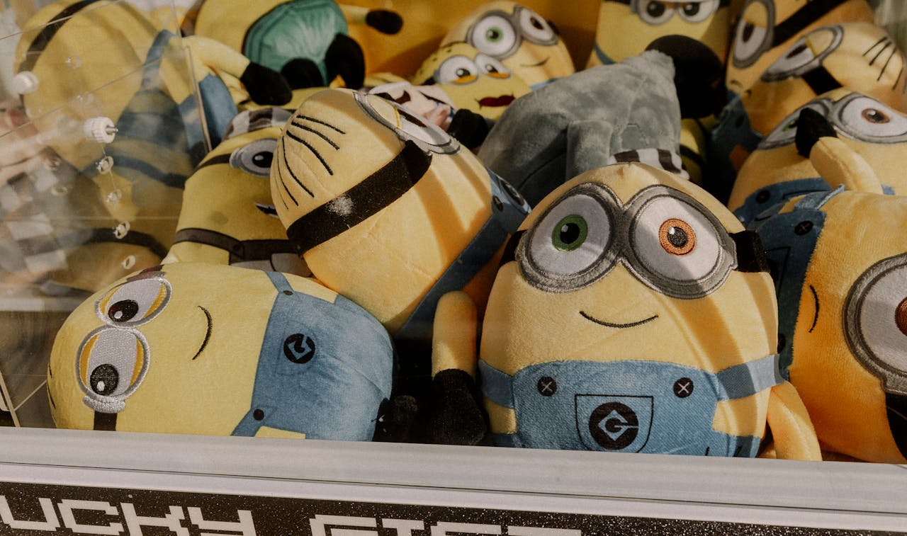 programs-02 A collection of vibrant minion plush toys inside an arcade claw machine, perfect for entertainment.